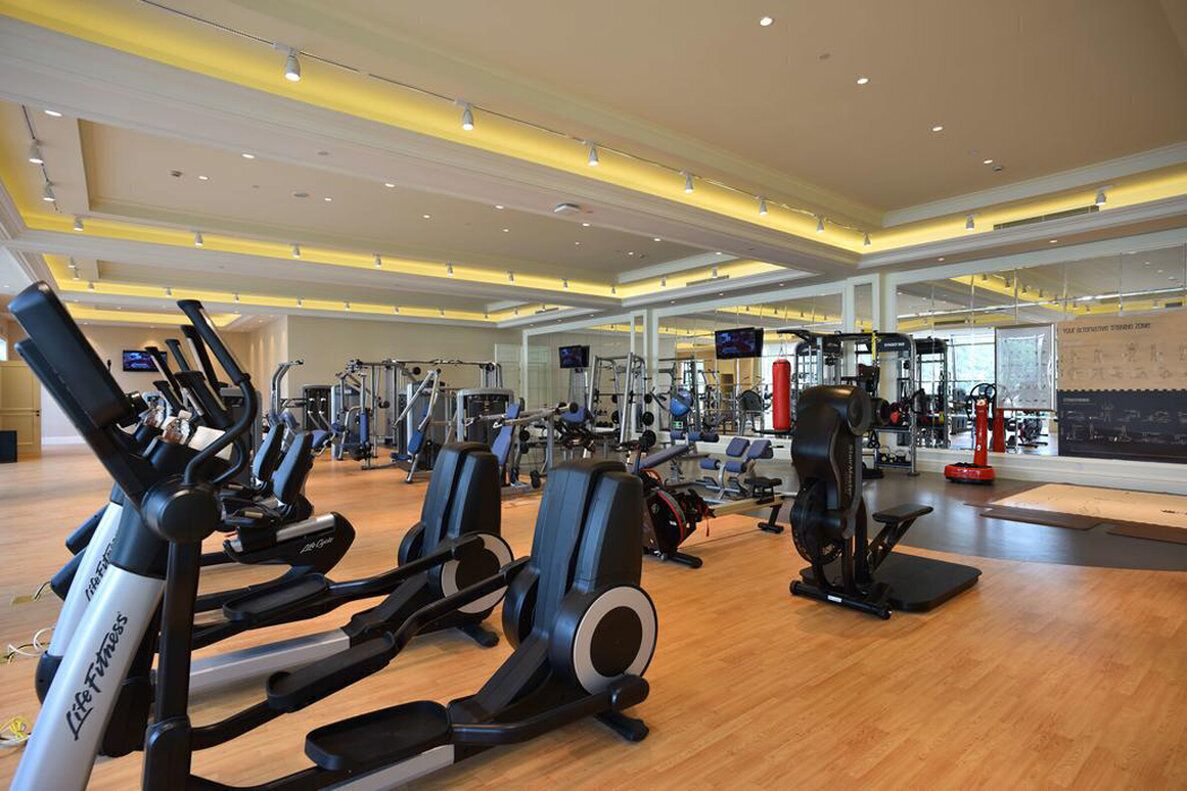 A gym with cardio machines, weightlifting equipment, and a large mirror.