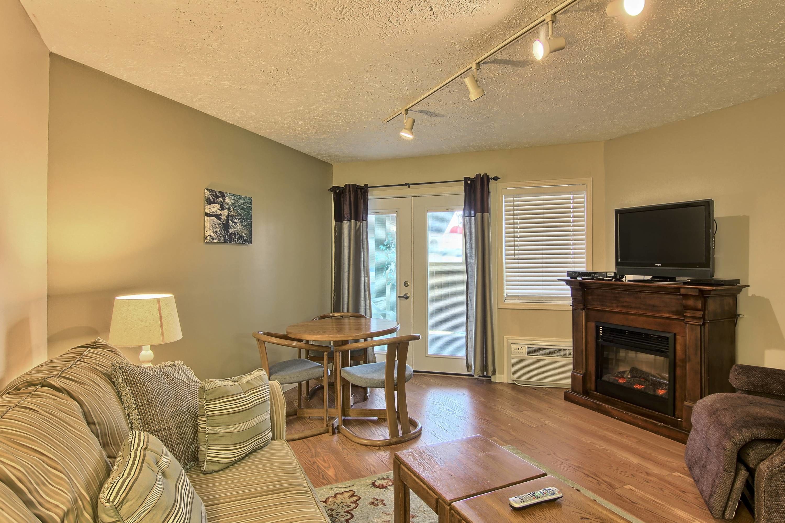 A living room with a sofa, a coffee table, a fireplace, a television, and a dining table with chairs.