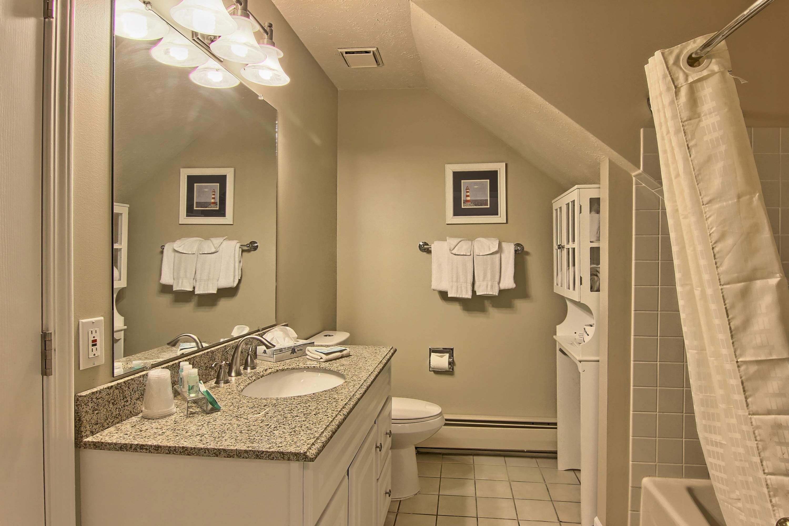A bathroom with a sink, mirror, and two framed pictures on the wall.