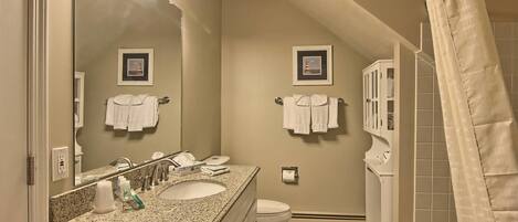 A bathroom with a sink, mirror, and two framed pictures on the wall.