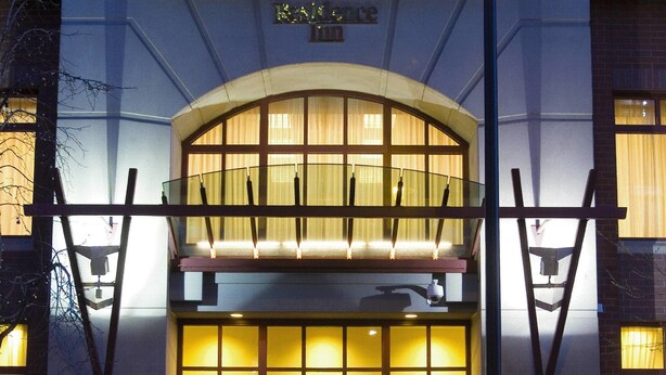 Entrada de hotel con puertas dobles, un letrero que indica que es un hotel y un área de estar al aire libre.
