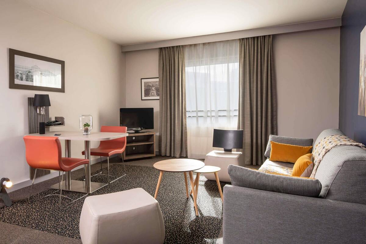 Une chambre d’hôtel moderne dotée d’un coin repas, d’un canapé et d’une télévision.