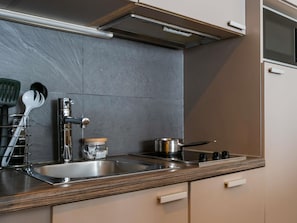 Een keuken met een roestvrijstalen spoelbak, een fornuis en een bestekhouder.