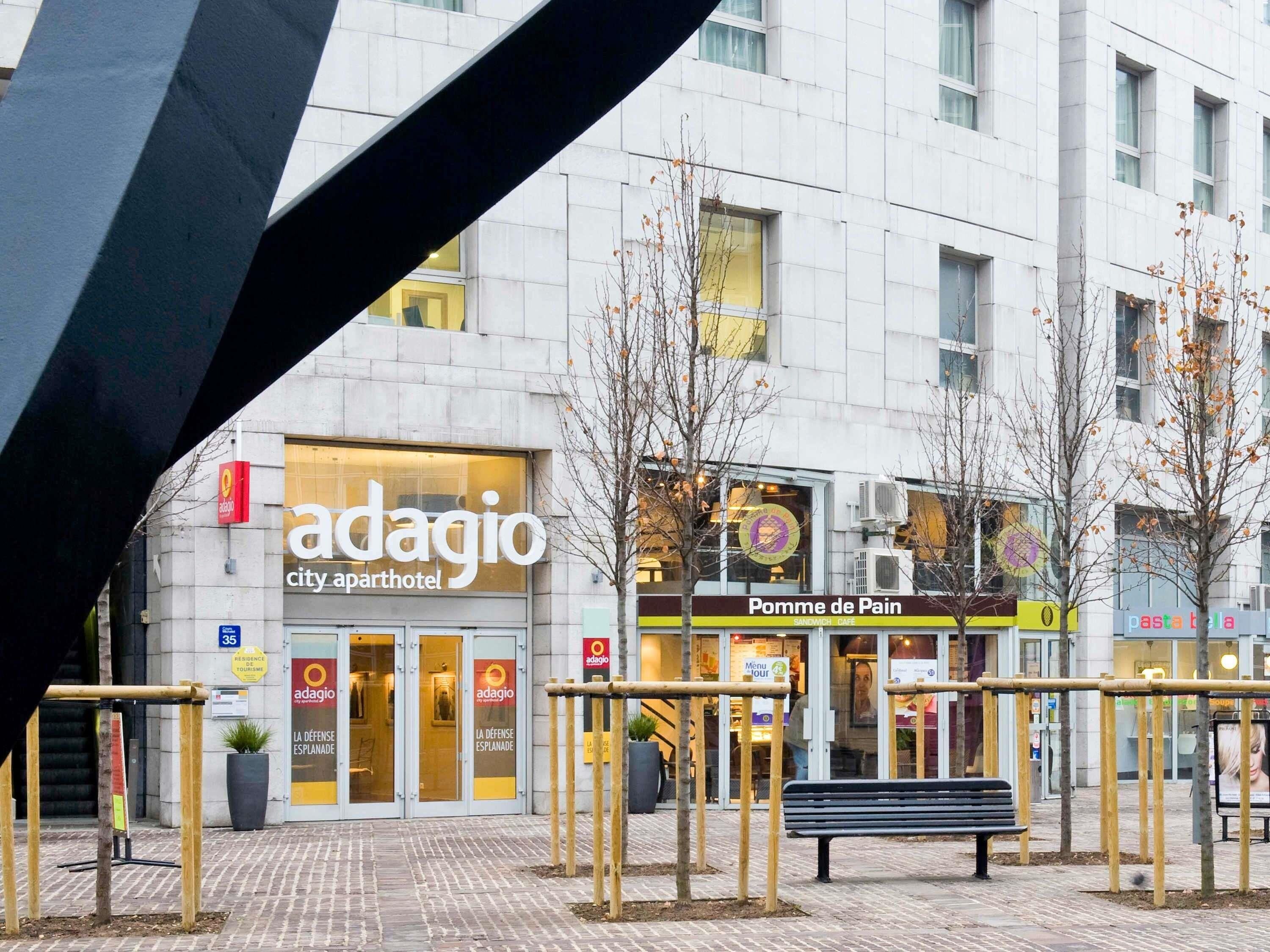 Een stadsbeeld met een appartementenhotel genaamd 'Adagio' en een broodjeszaak 'Pomme de Pain' op de achtergrond.