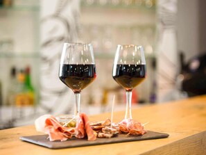Two wine glasses on a wooden table with a selection of cured meats.