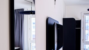 A hotel room with a bed, a TV, a wardrobe, and a mirror. - ibis Rodez Centre Cathédrale (Rodez)