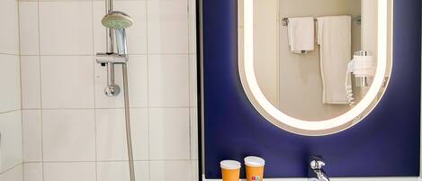 Un baño con ducha, lavabo y espejo.