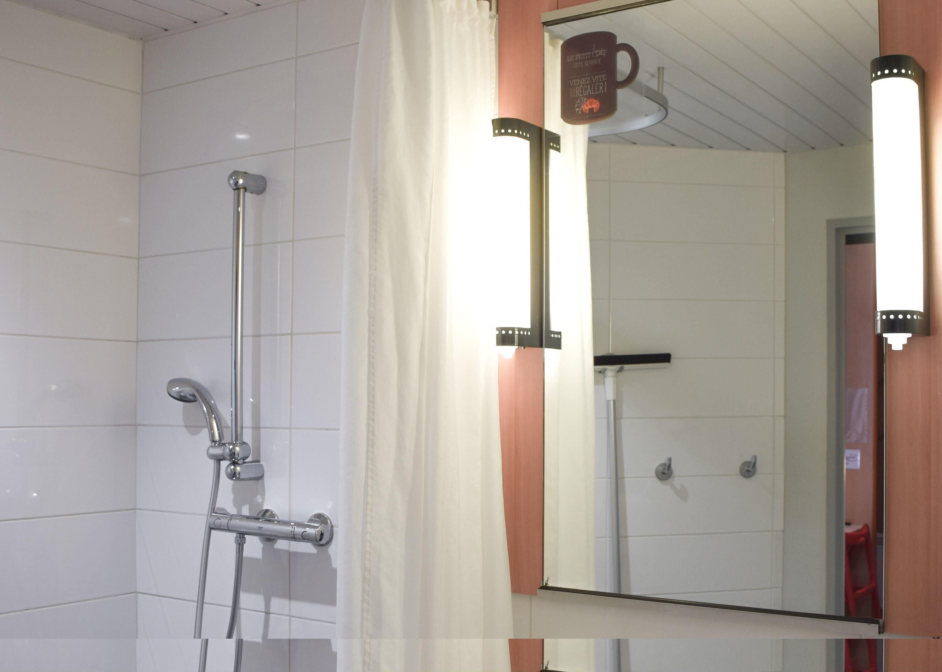 A bathroom with a shower, a mirror, and a towel rack.