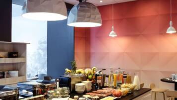 Un bufé de desayuno con diversos alimentos y bebidas, iluminación colgante geométrica y una decoración de interiores moderna.