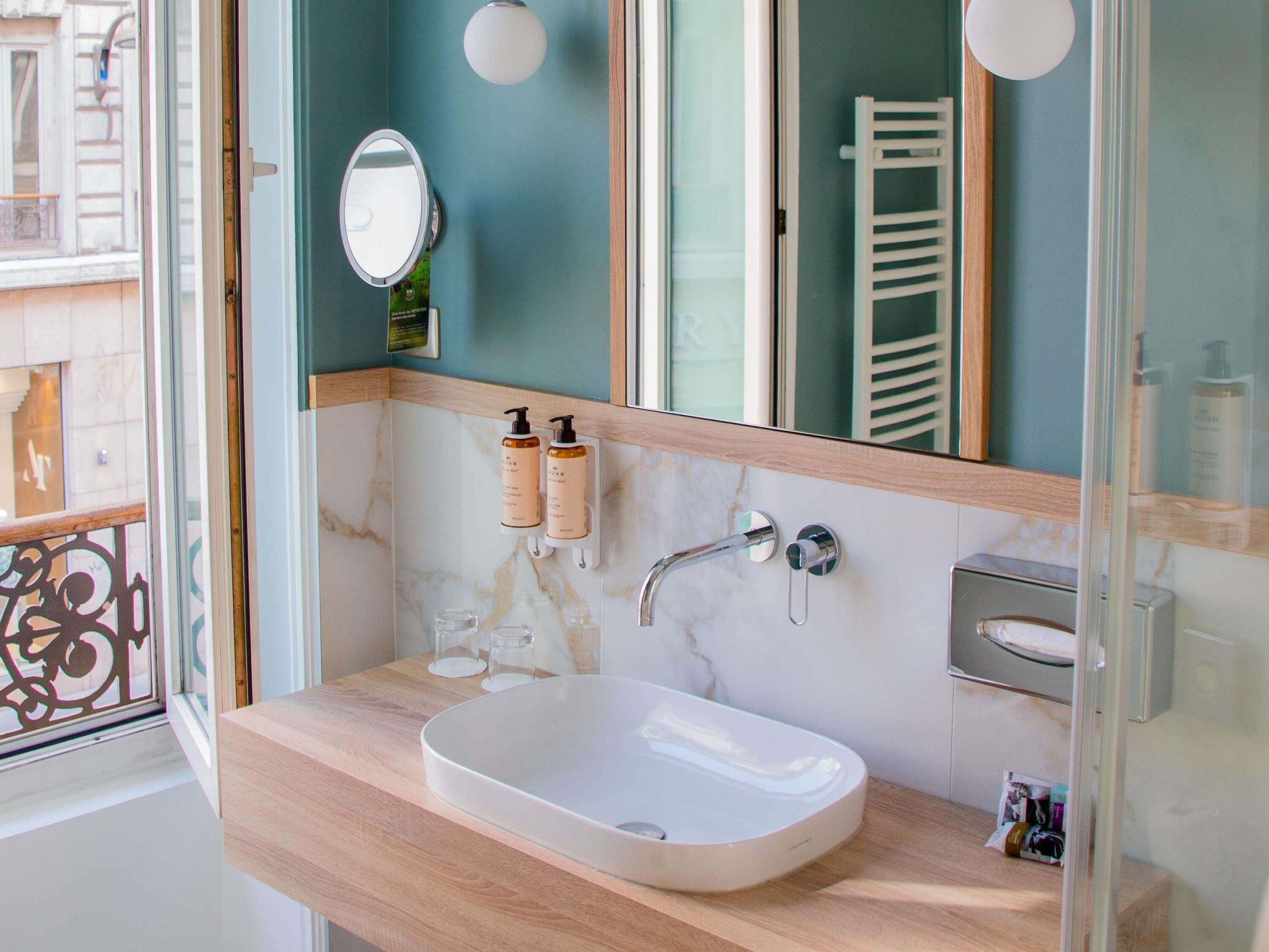 A bathroom with a white sink, a mirror, a towel rack, and two bottles of lotion.