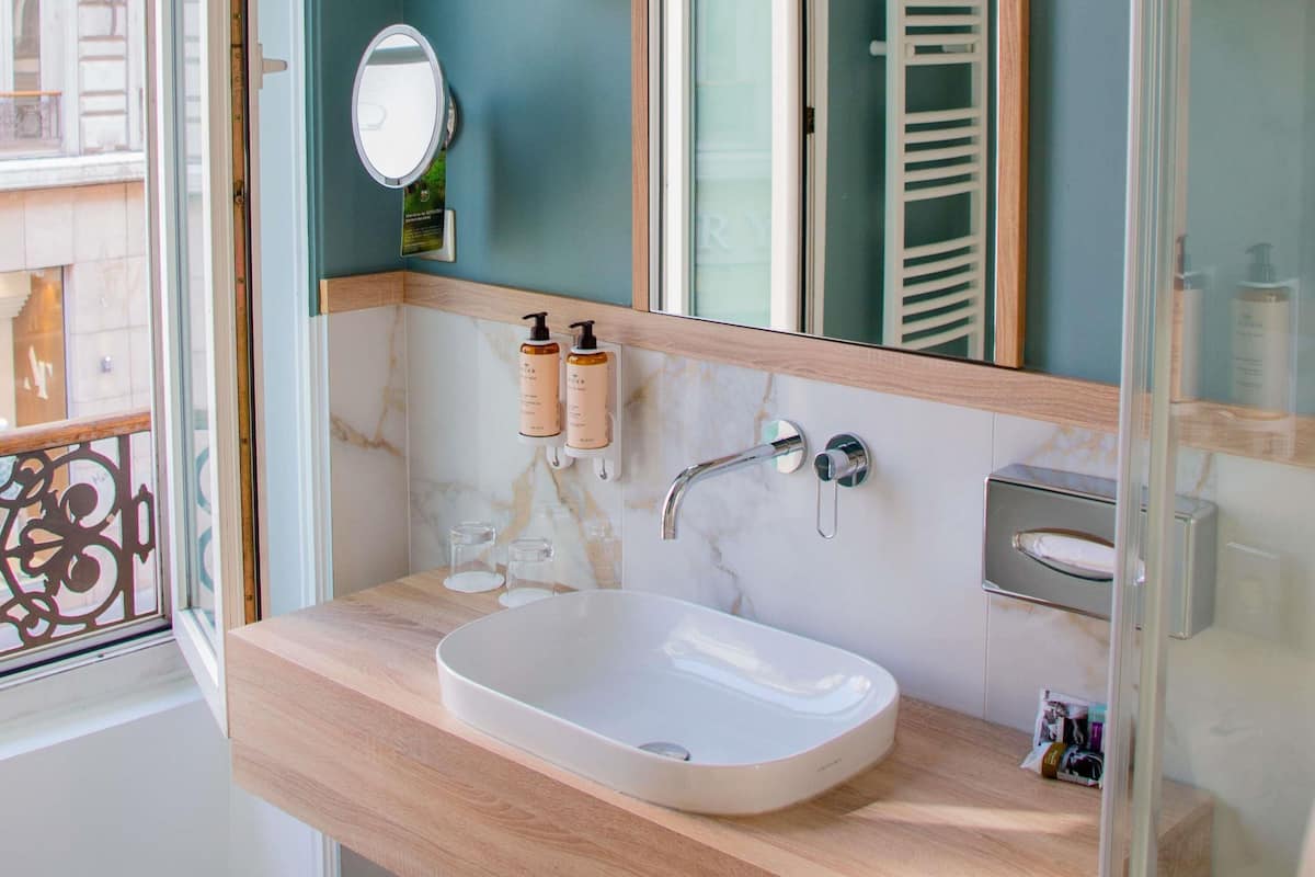 A bathroom with a white sink, a mirror, a towel rack, and two bottles of lotion.