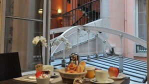 A breakfast table with a bowl of fruit, a cup, and a vase of flowers. - Mercure Lyon Centre Beaux Arts (Lyon)
