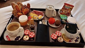A hotel room with a breakfast tray, a cup of coffee, a teapot, and a view of buildings through the window. - Mercure Lyon Centre Beaux Arts (Lyon)