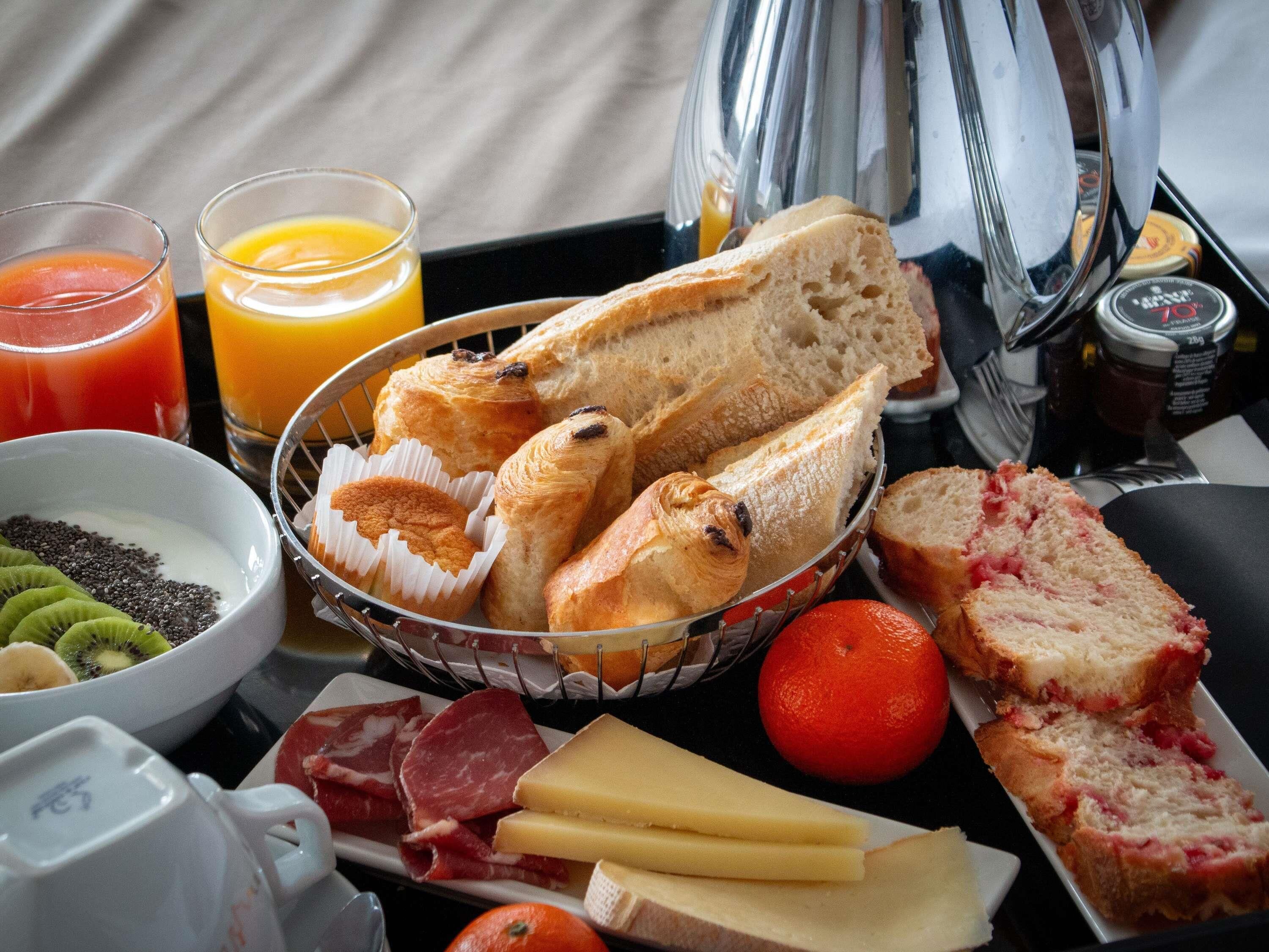 Bandeja de desayuno con pan, bollería, queso, embutidos y frutas.