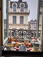 Un vassoio con caffè, pasticcini e frutta su un balcone affacciato sui palazzi parigini.