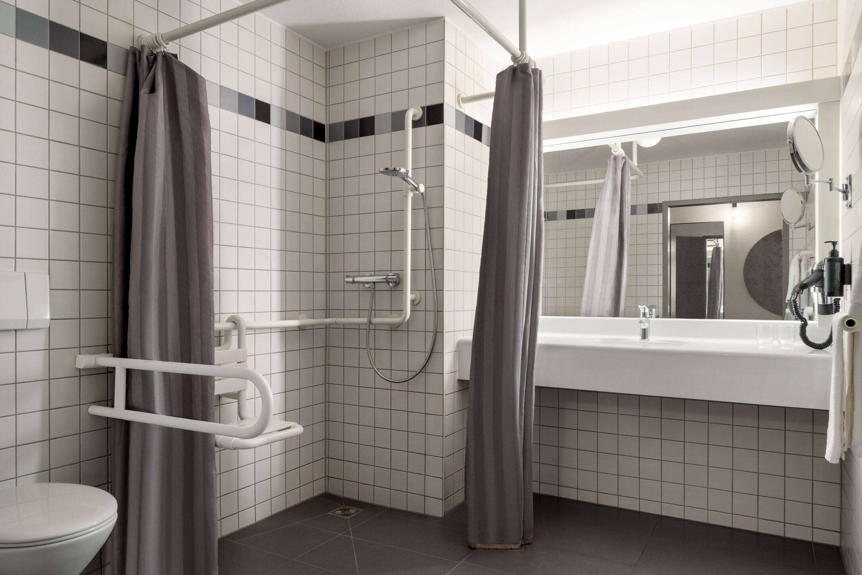Un baño moderno con lavamanos blanco, espejo y zona de ducha.