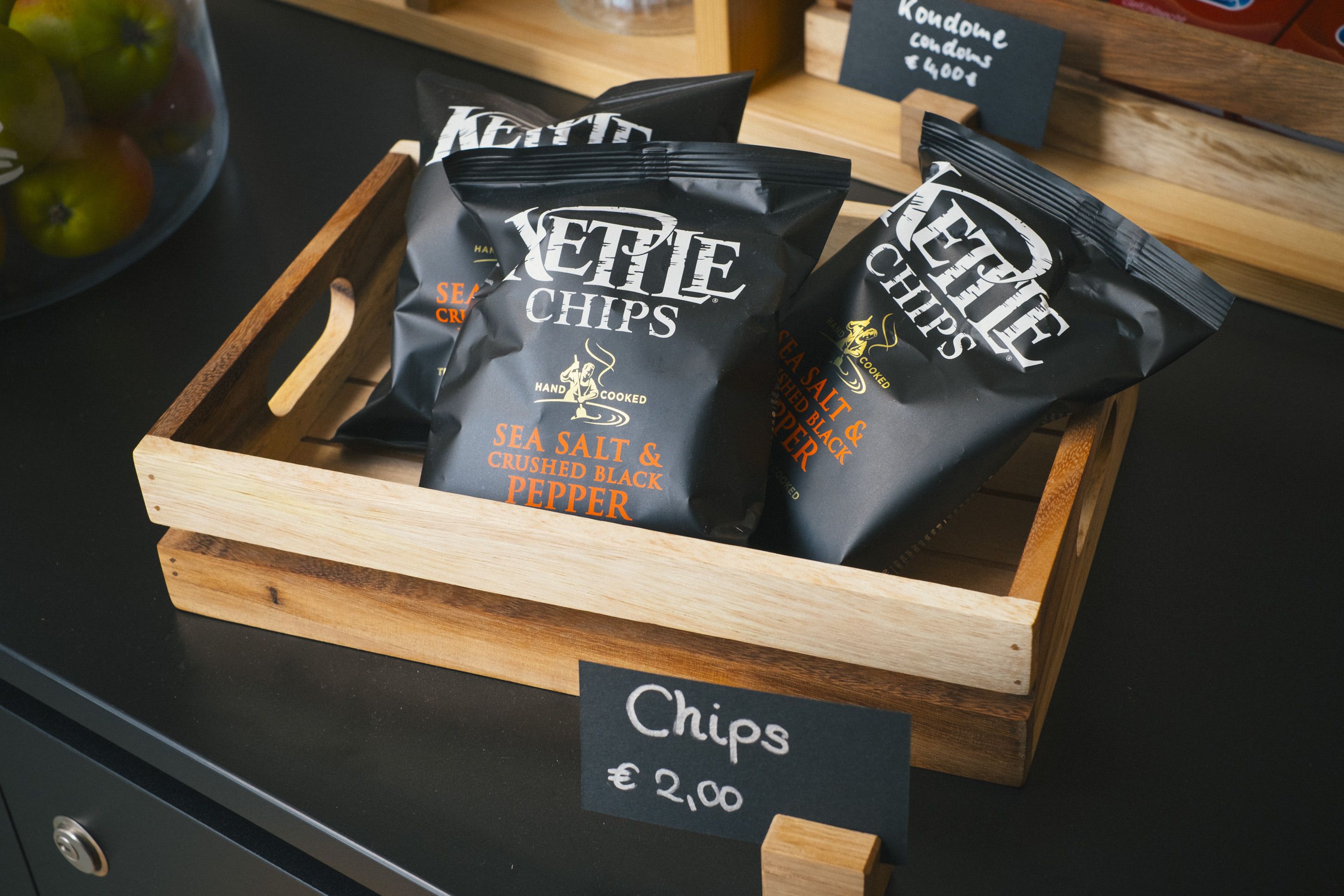 Un plateau en bois contenant des sachets de sel marin et des éclats de poivre noir concassé, le tout vendu au prix de 2,00 €.
