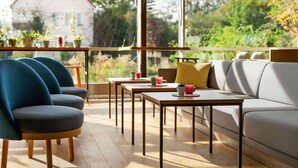 Un espace extérieur moderne aménagé avec un canapé et des fauteuils, des tables en bois et des plantes en pot.