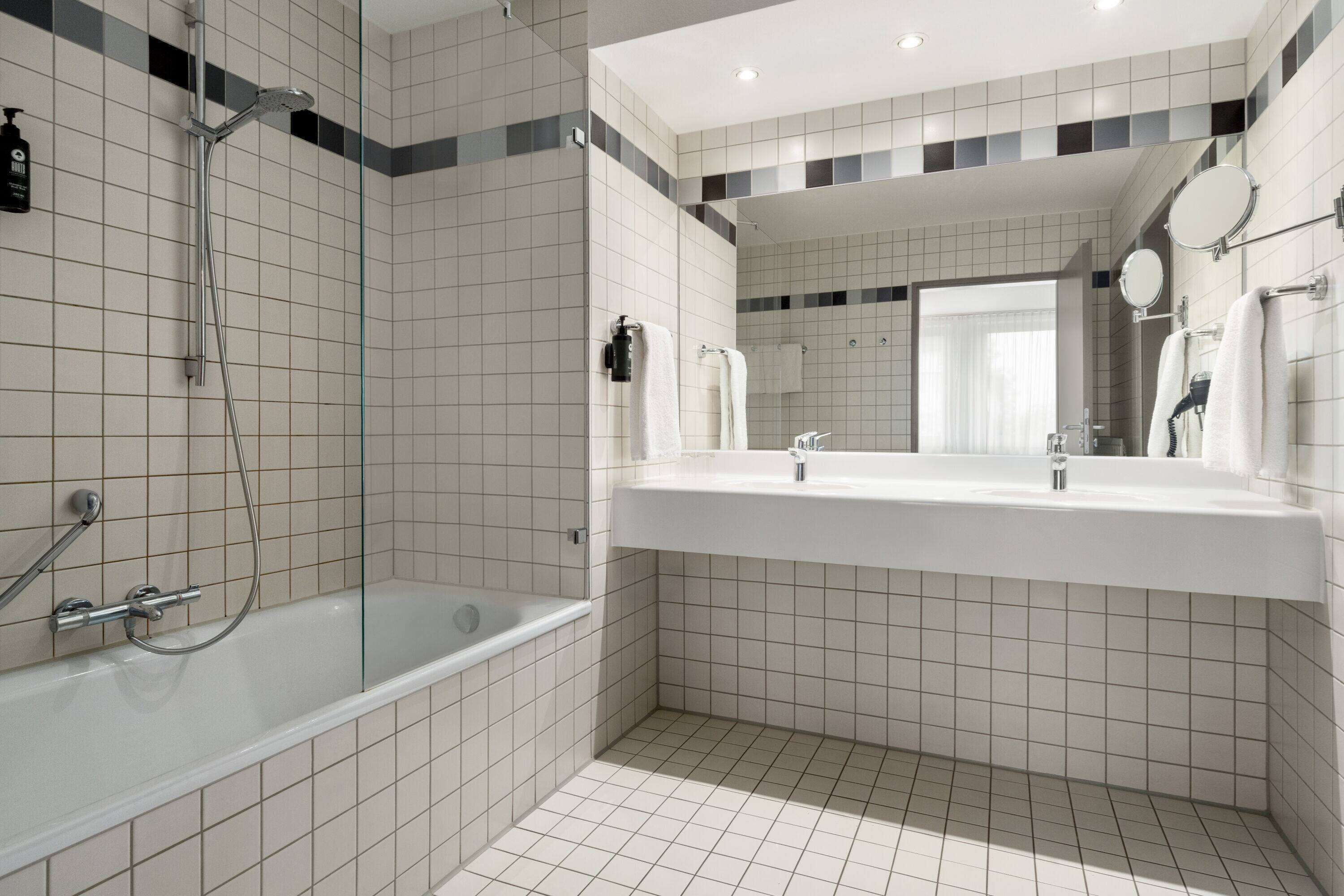 Ein modernes Badezimmer mit einer Duschkabine, einem großzügigen Waschtisch mit Spiegel und einer Badewanne.