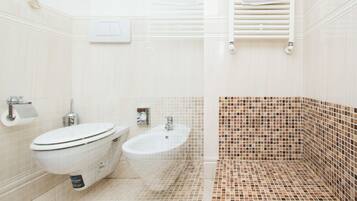 A bathroom with a toilet, bidet, and a sink.