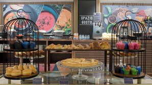 Una vitrina de pastelería con varios productos de repostería y postres, incluyendo cruasanes y tartas, en un ambiente de cafetería.