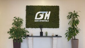 Un mostrador de recepción con un logotipo, dos plantas en macetas y un cactus.