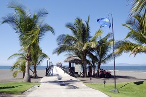 Stroll along the coastal walkway, flanked by palm trees, to a serene beach area.