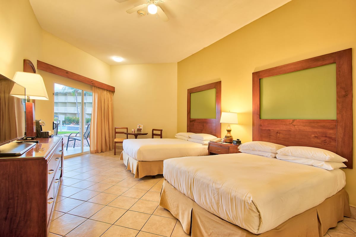 A hotel room with two beds, a desk, a chair, and a view of the outside.