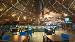 A spacious indoor dining area with high ceilings, a central bar, and multiple seating arrangements.