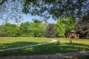 A park with a playground, a clear path, and lush greenery. - Park Hotel Junior (Quarto d'Altino)