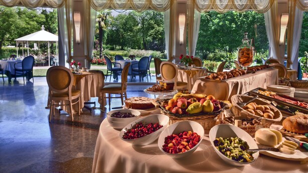 An outdoor dining area with tables set for breakfast, featuring a variety of fruits and pastries. - Park Hotel Junior (Quarto d'Altino)
