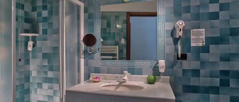 Baño con lavamanos, espejo y ducha.