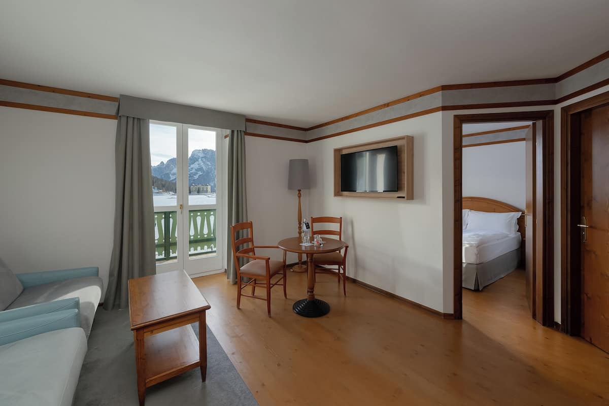 Une chambre d’hôtel avec un plancher en bois, un canapé, une table, une télévision et un lit.