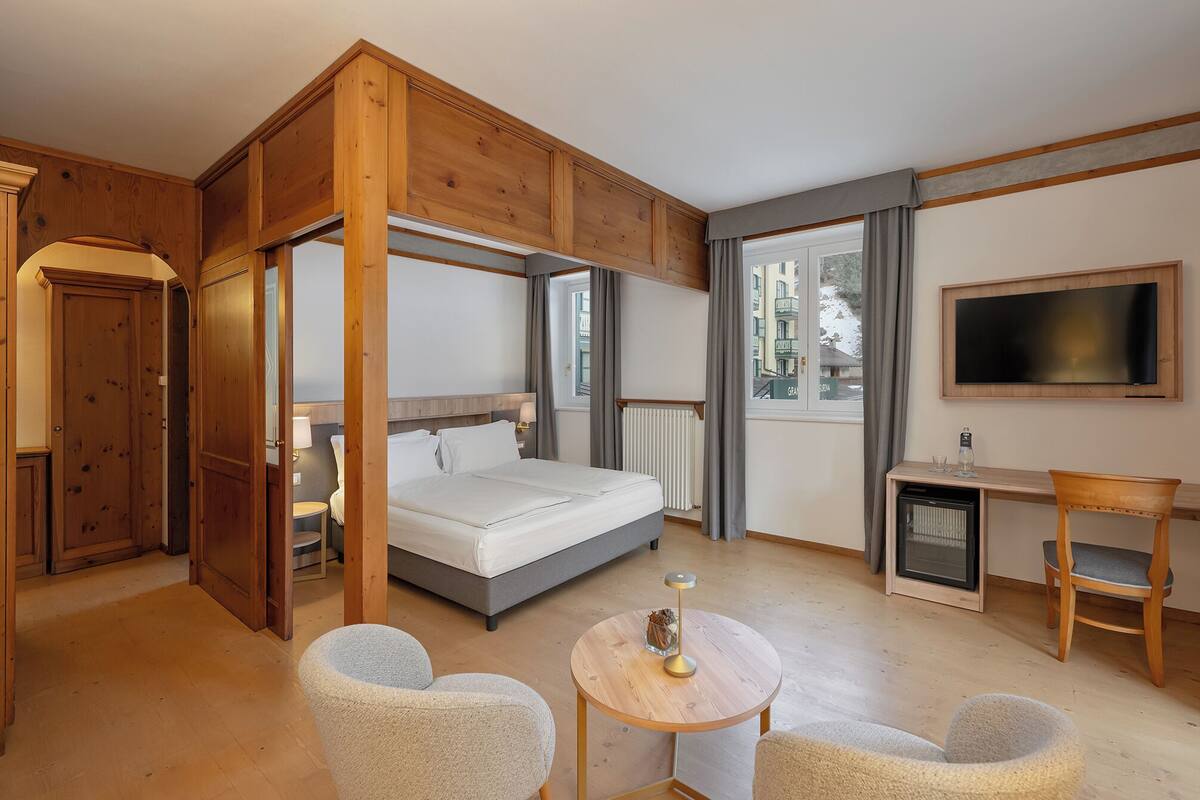 Une chambre à coucher avec un lit à baldaquin, un bureau, une chaise et un téléviseur.