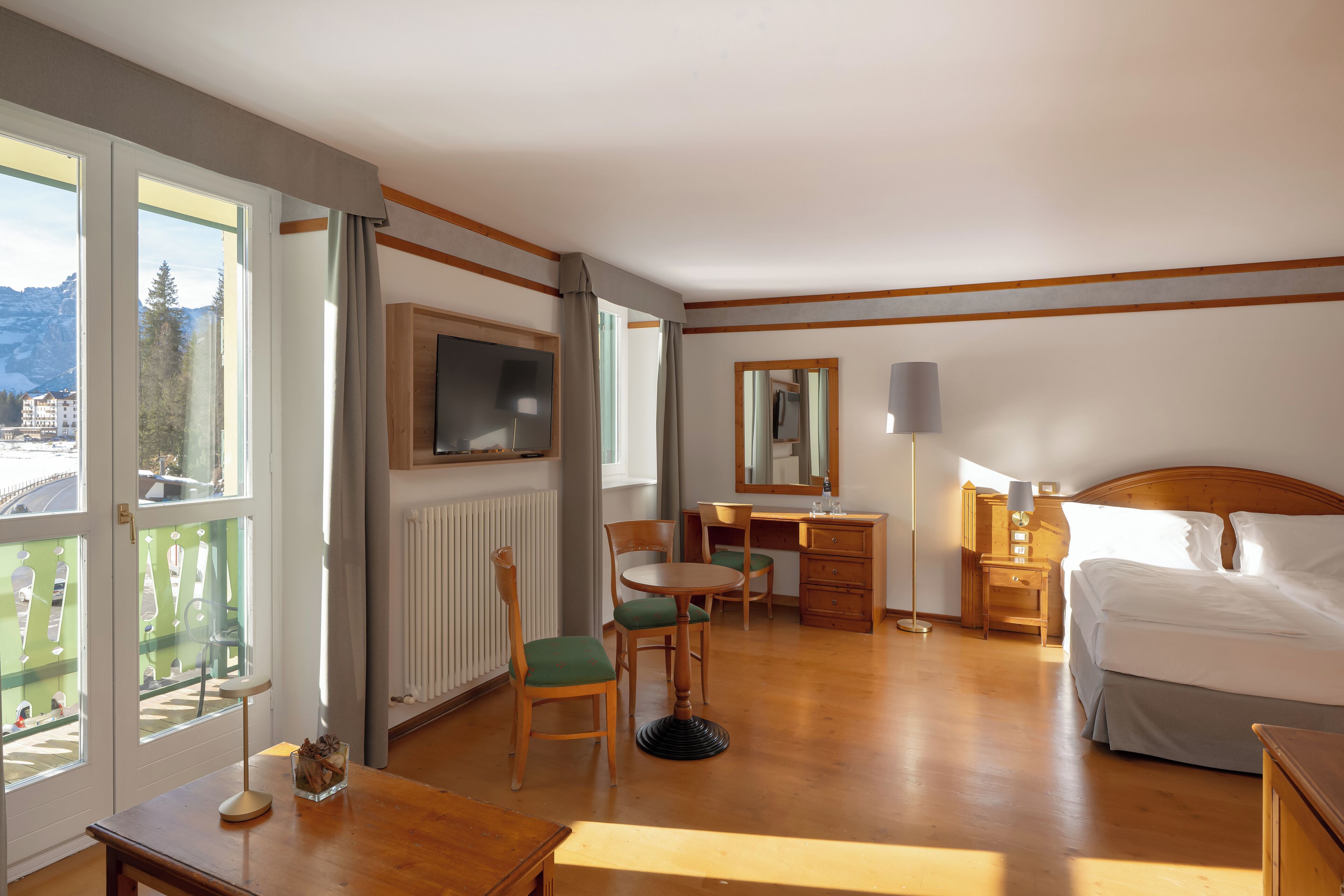 Habitación de hotel con cama, escritorio, silla, televisor y vista al exterior.