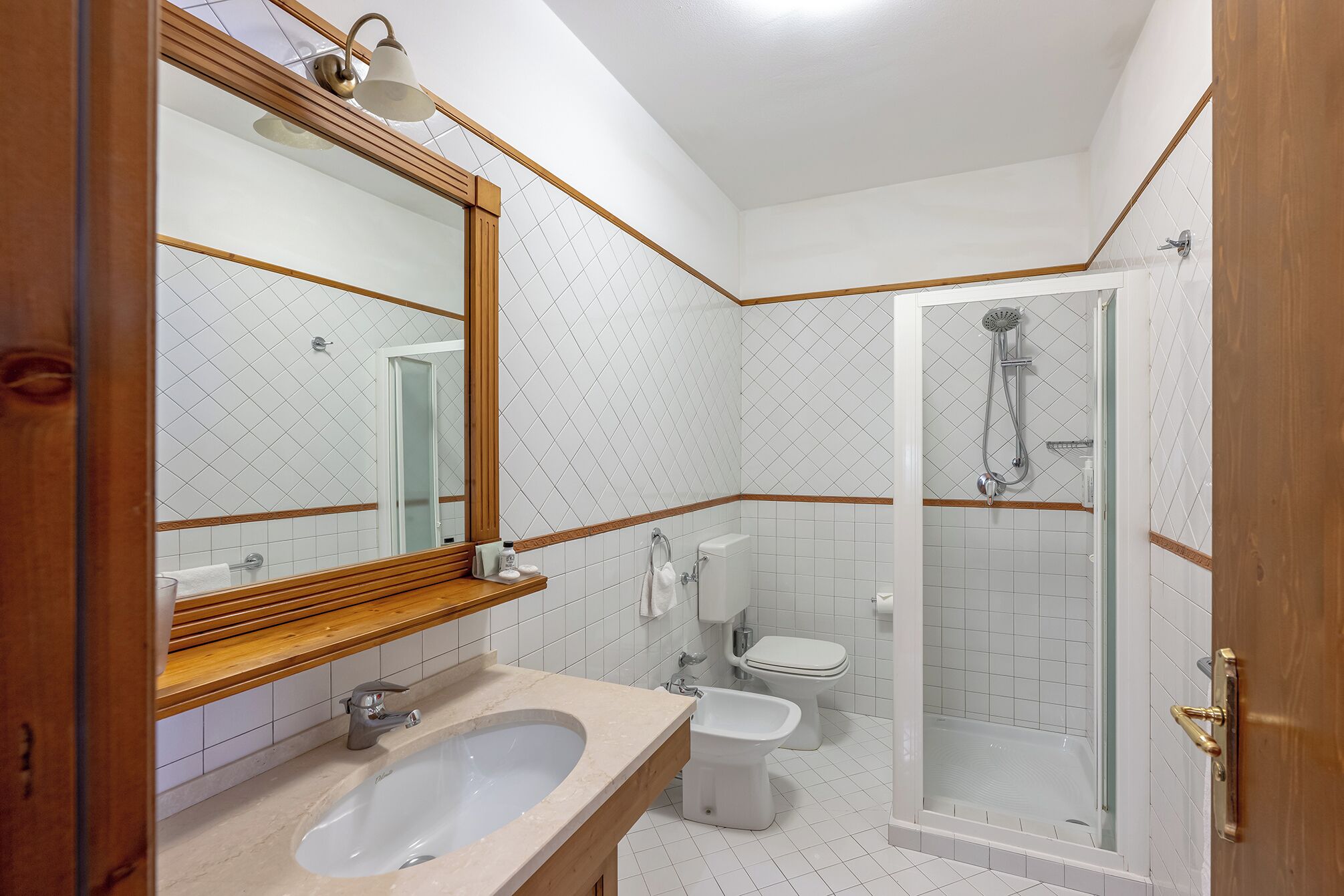 A bathroom with a sink, bidet, toilet, and shower.