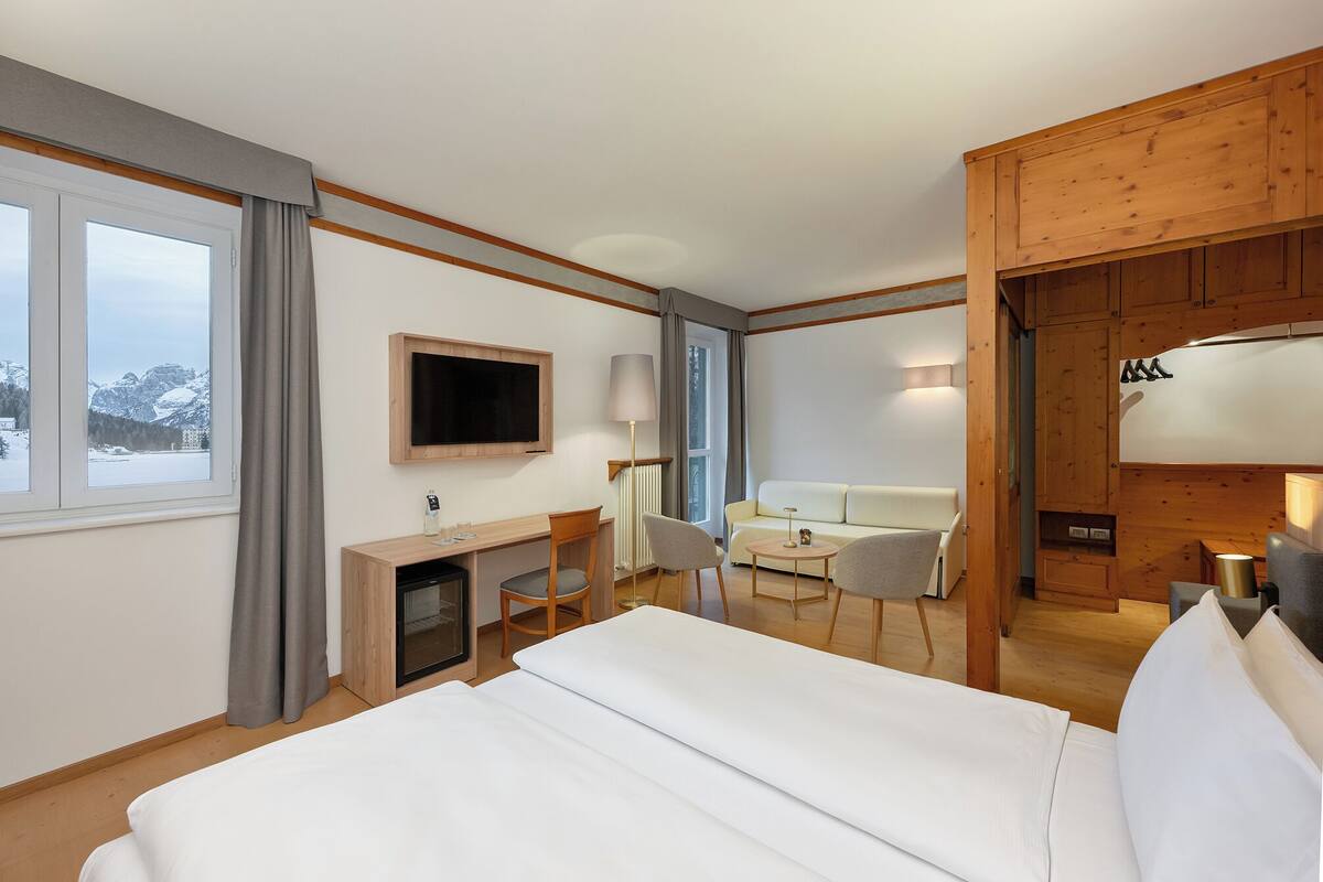 Une chambre d’hôtel équipée d’un lit, d’un bureau, d’une chaise, d’un canapé et d’une télévision.