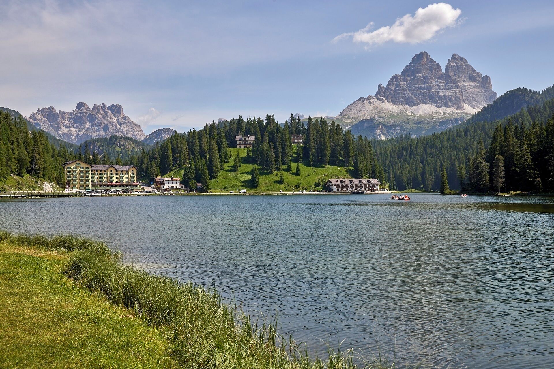 A lakeside hotel with multiple buildings, a dock, and a mountainous backdrop.