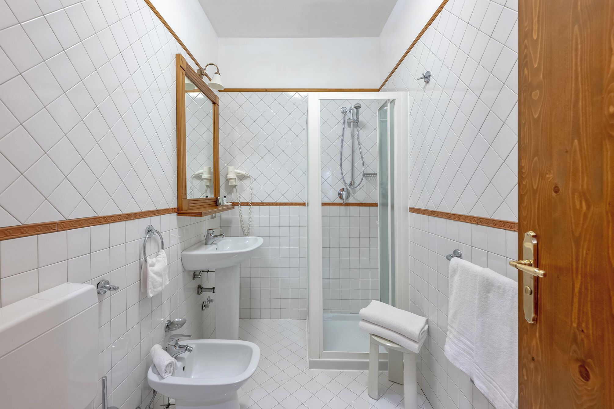 Un baño moderno con ducha, dos lavamanos, un bidé y un inodoro.