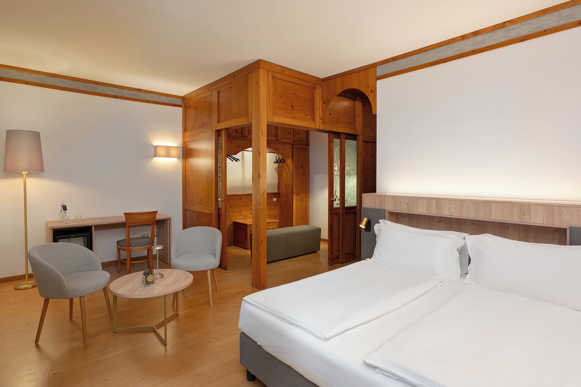 Een hotelkamer met een bed, een bureau, twee stoelen, een lamp en een kledingkast.