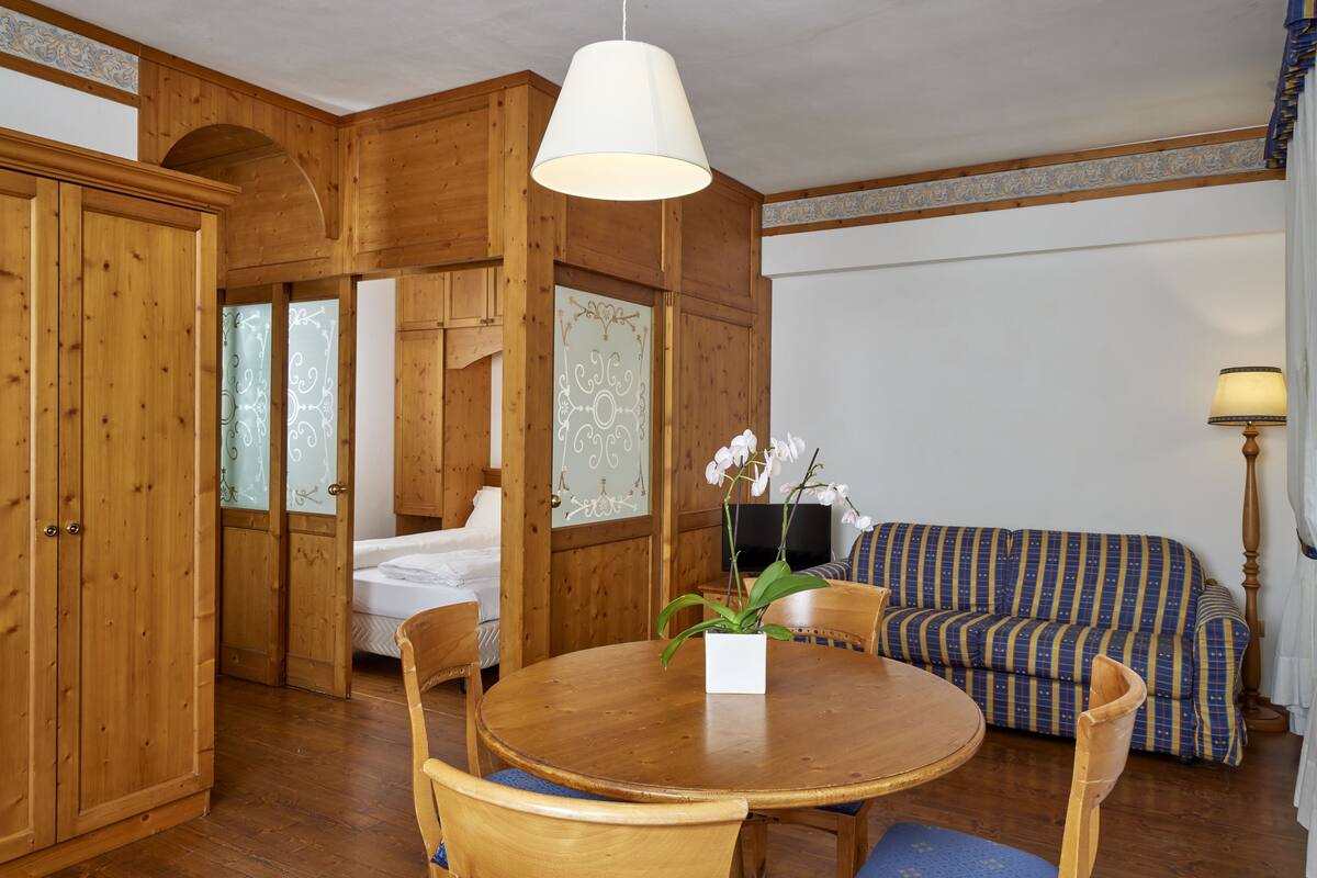 Une pièce en bois avec une table à manger ronde, des chaises, un canapé et un téléviseur.