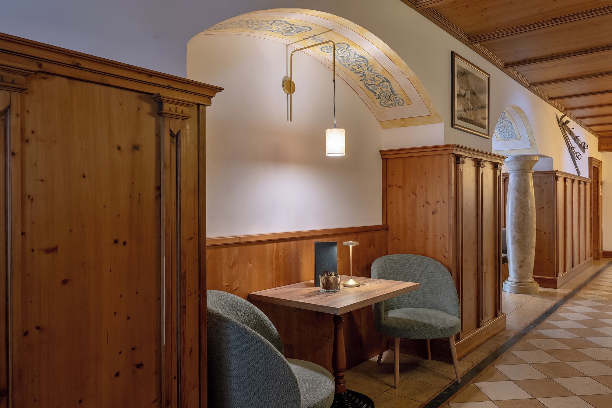 Un restaurant avec des murs lambrissés, un sol à carreaux et une table entourée de chaises.