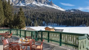Terraço com área de estar ao ar livre, com vista para uma paisagem nevada e uma montanha.