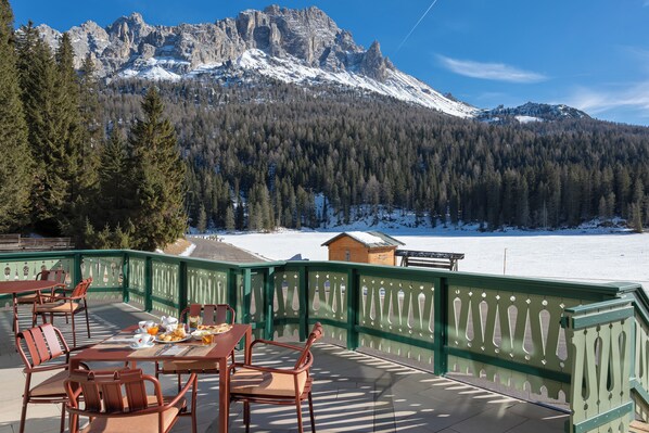 Una terrazza con posti a sedere all'aperto, con vista su un paesaggio innevato e una montagna.