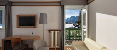 A modern living room with a sofa, a TV, a table, and a view of a snowy mountain landscape.