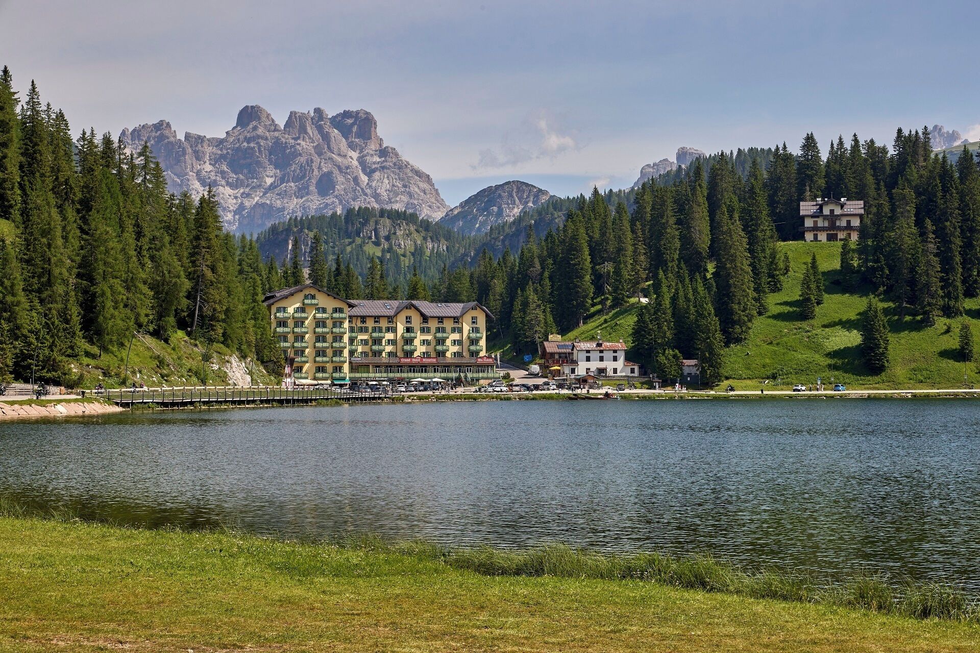 Un hotel con varias construcciones, un lago y montañas al fondo.