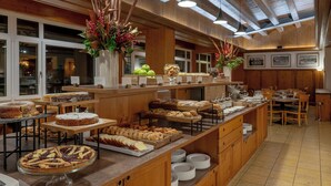 Uma área de buffet com diversos alimentos, incluindo tortas, doces e frutas.