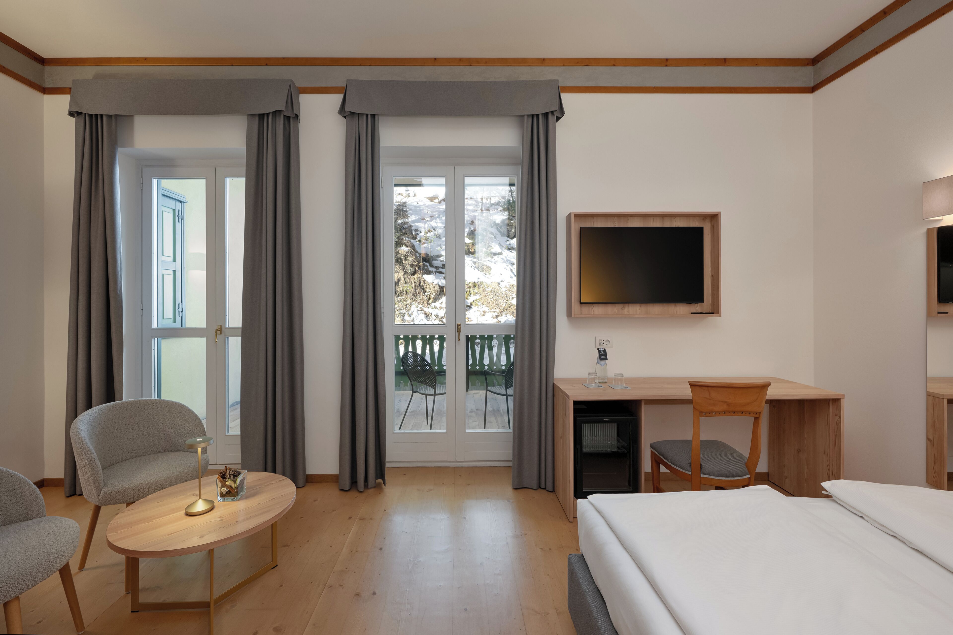 Una camera d'albergo con un letto, una scrivania, una sedia, una TV e vista sull'esterno.