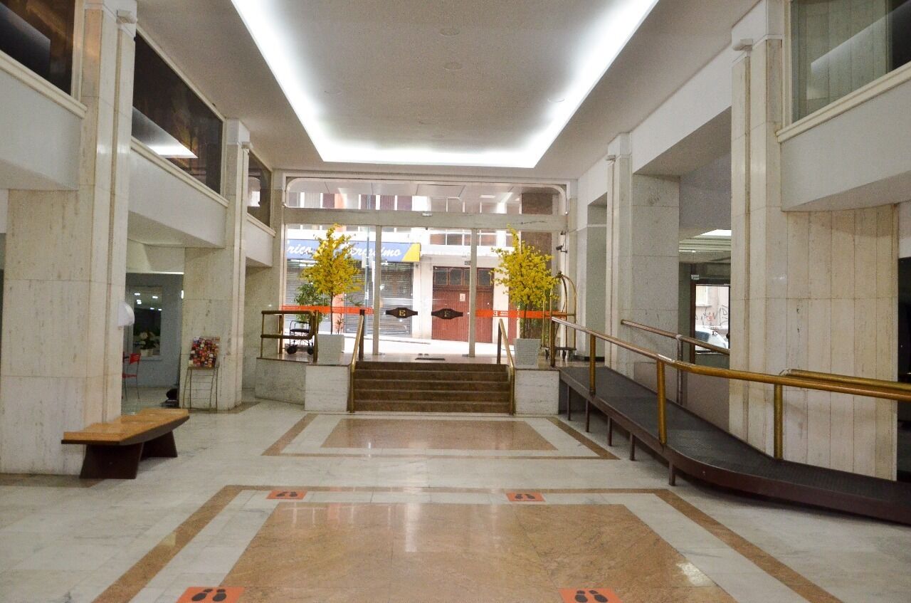 A spacious lobby with a marble floor, a central staircase, and a bench.
