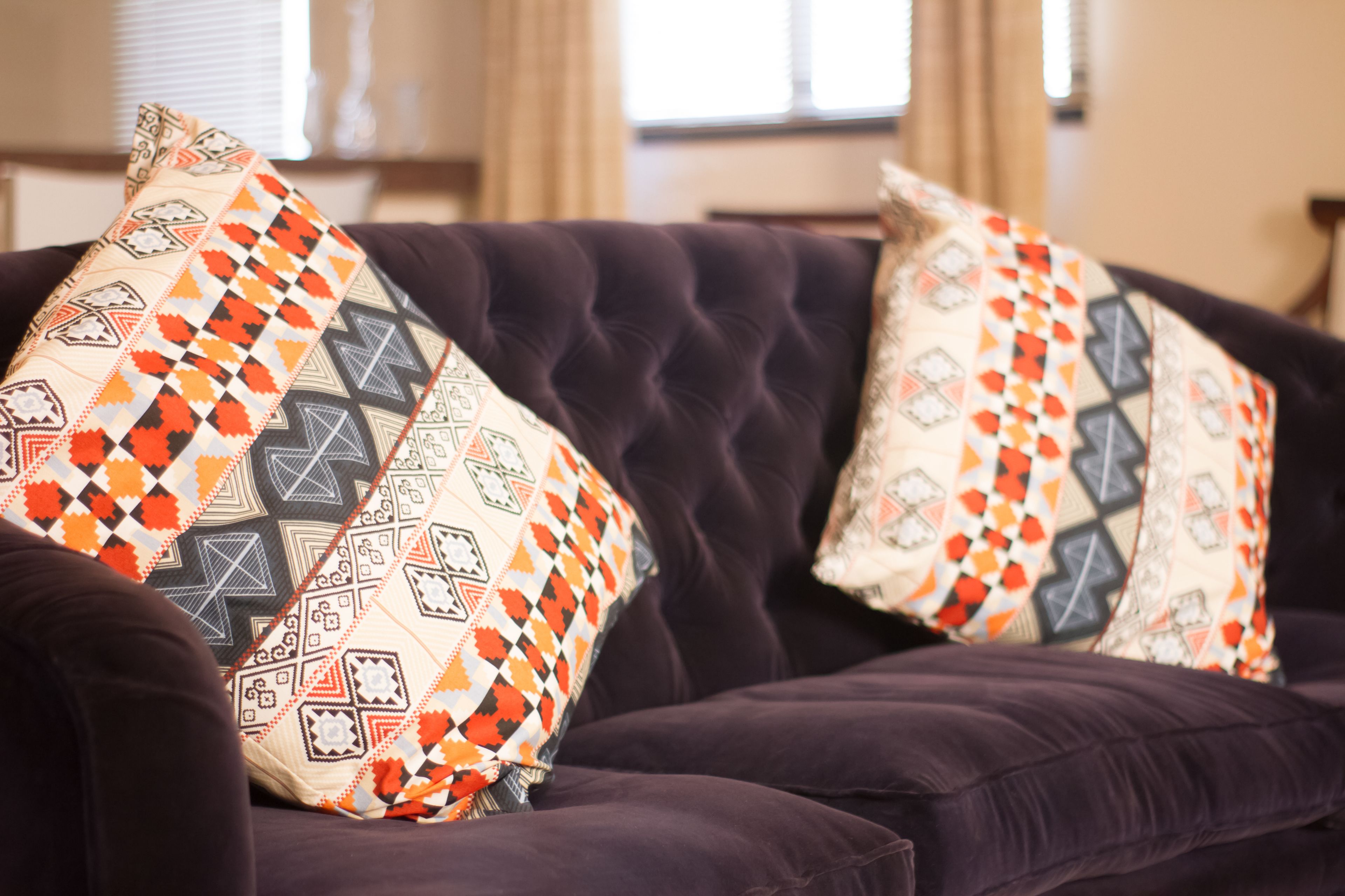 Ein dunkelviolettes Sofa mit gemusterten Kissen.